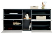 Modernes Sideboard/Schuhschrank in Weiß mit dunkelgrauen Fächern, drei nach unten öffnenden Klappen und offenen Regalen, dekoriert mit Boxen, Vase und Lampe; Frontalansicht.