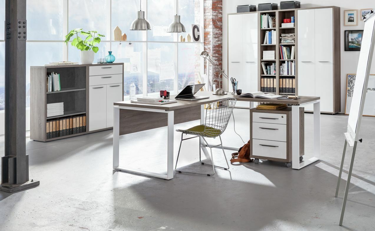 Moderner Eck-Schreibtisch mit Rollcontainer und Regal in einem hellen, industriellen Büro mit großen Fenstern, seitliche Perspektive.