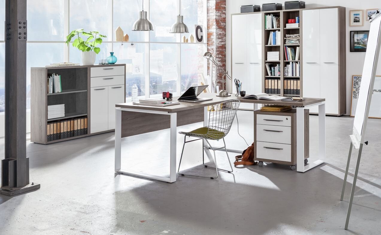 Moderner Eck-Schreibtisch mit Rollcontainer und Regal in einem hellen, industriellen Büro mit großen Fenstern, seitliche Perspektive.