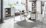 Moderner Eck-Schreibtisch mit Rollcontainer und Regal in einem hellen, industriellen Büro mit großen Fenstern, seitliche Perspektive.