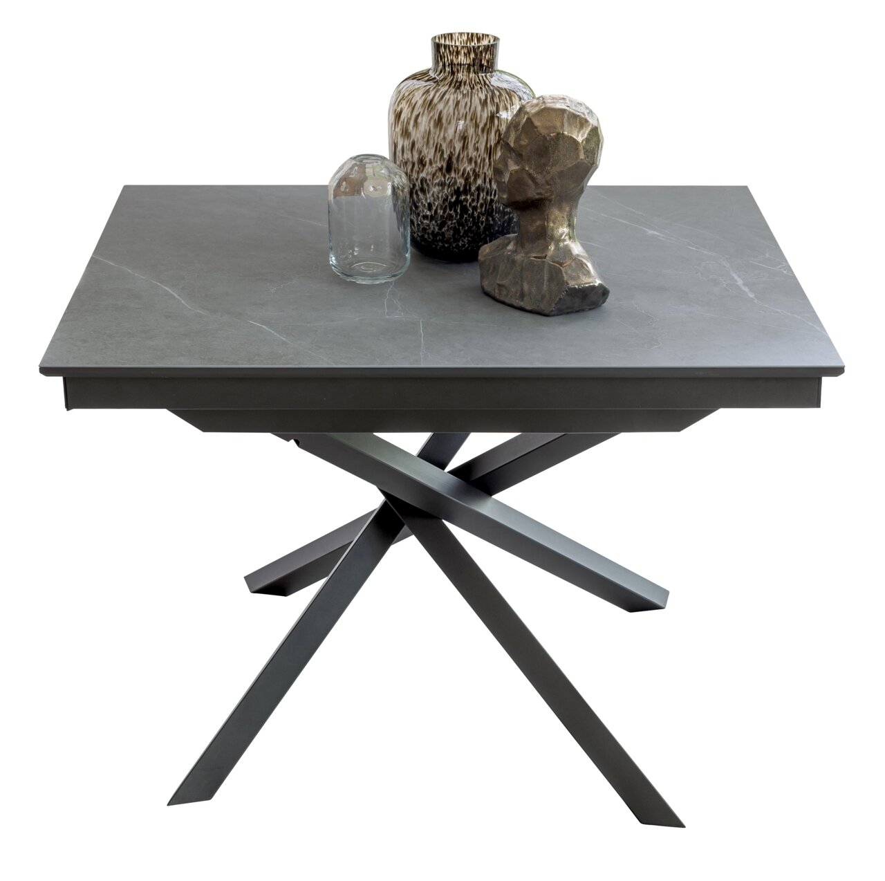 Moderner Esstisch TOKYO mit grauer Tischplatte und stilvollem, gekreuztem Metallgestell, dekoriert mit Vasen und Skulptur, aus seitlicher Perspektive.