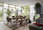 Moderner Esstisch aus Holz mit Metallbeinen, umgeben von stilvollen Stühlen und einer Bank, in einem hellen Raum mit großen Fenstern, seitliche Perspektive.