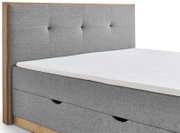 Graues Boxbett mit gepolstertem Kopfteil und Holzrahmen, seitliche Perspektive