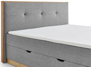 Graues Boxbett mit gepolstertem Kopfteil und Holzrahmen, seitliche Perspektive