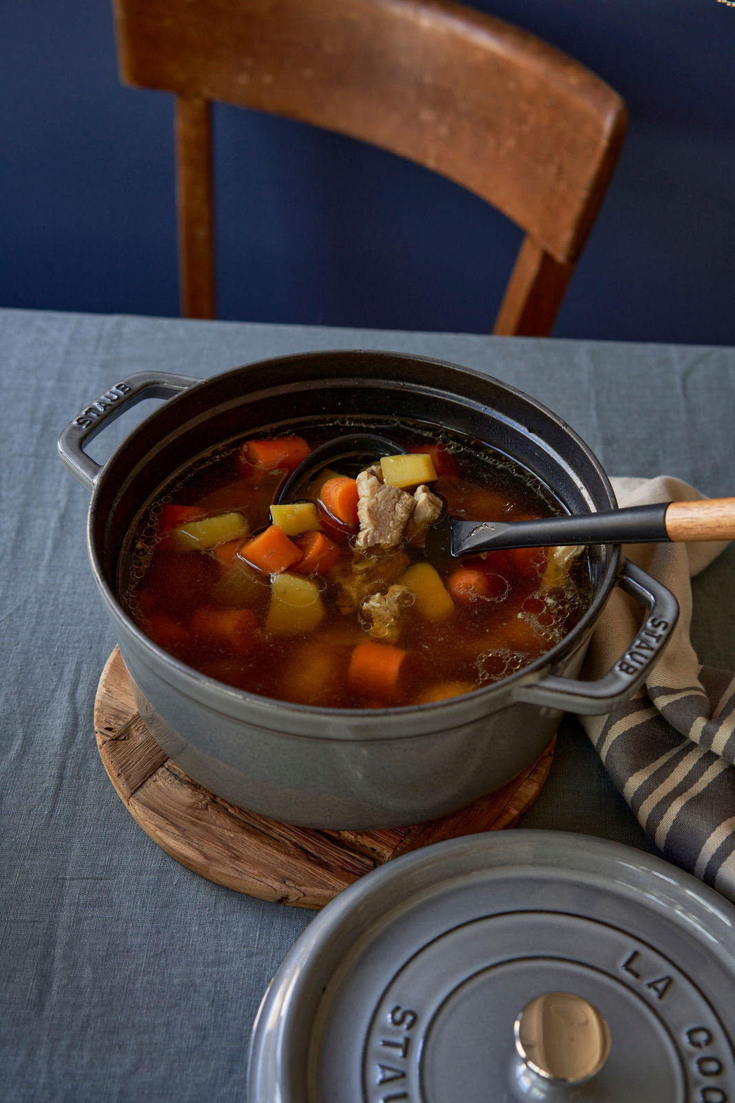 Runder Bräter Cocotte 24cm in Grau, gefüllt mit Eintopf, auf einem Tisch von oben fotografiert.