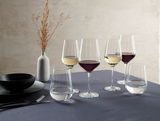Ein stilvoll gedeckter Tisch mit einem 12er-Set Weingläser im Sternschliff-Design, gefüllt mit Rot- und Weißwein, aus seitlicher Perspektive fotografiert.