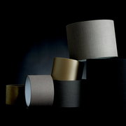 Mehrere Lampenschirme in verschiedenen Farben und Texturen, gestapelt in einer künstlerischen Anordnung, seitliche Perspektive