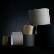 Mehrere Lampenschirme in verschiedenen Farben und Texturen, gestapelt in einer künstlerischen Anordnung, seitliche Perspektive