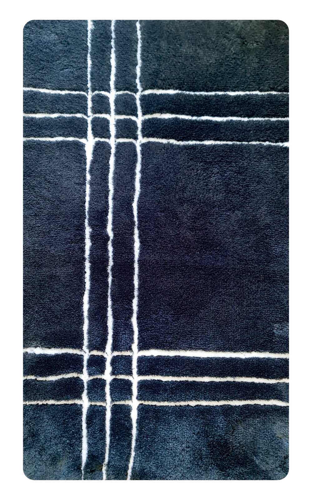 Dunkelblauer Badteppich mit weißen Linien in einem karierten Muster, aus der Vogelperspektive fotografiert.