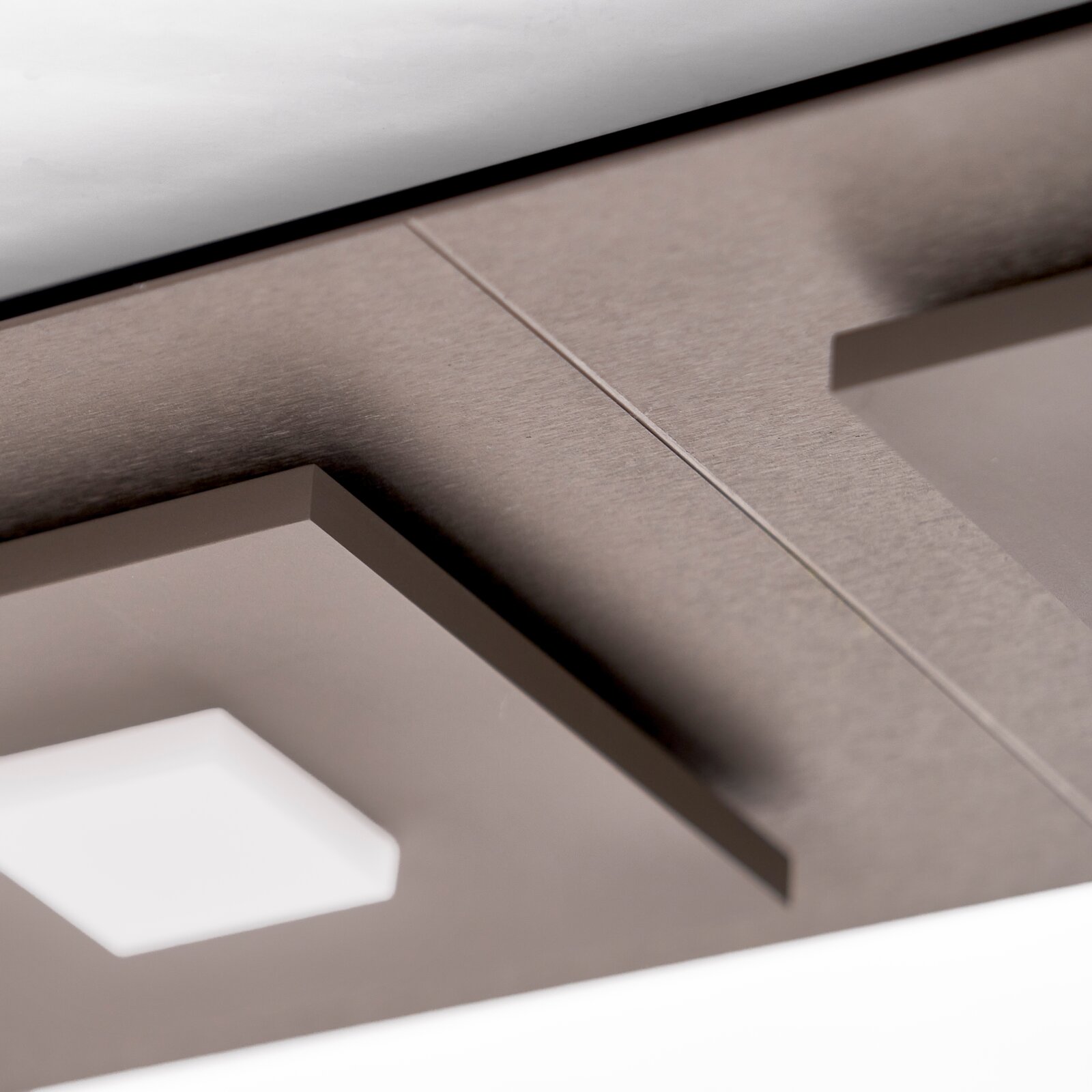 Detailaufnahme aus der Untersicht eines modernen Möbelstücks in Grau mit strukturierter Holzoptik und geometrischen Aussparungen