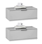 Zwei moderne, graue Nachtkonsolen mit einer Tasse und Büchern darauf, seitliche Perspektive.