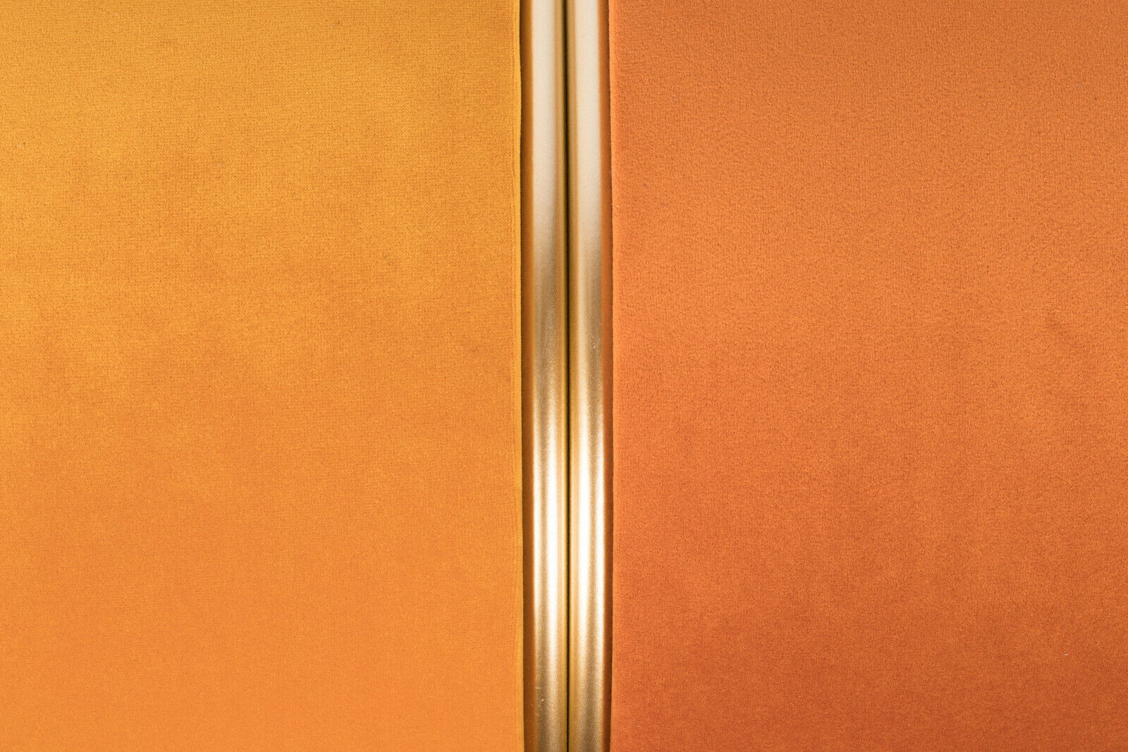 Nahaufnahme eines Hockers mit zweifarbiger Polsterung in Gelb und Orange, getrennt durch eine goldene Linie.