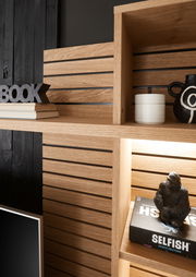 Nahaufnahme eines modernen Holzregals mit dekorativen Gegenständen, darunter Bücher, eine schwarze Vase und eine Gorilla-Figur. Perspektive von schräg oben.