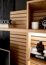Close-up van een moderne houten boekenkast met decoratieve voorwerpen, waaronder boeken, een zwarte vaas en een gorillafiguur. Opname vanuit een schuin bovenaanzicht.