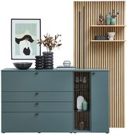 Moderne Sideboardkombination VANYA von Venjakob in stilvollem Design, mit grünen Schubladen und Glastür, dekoriert mit Vasen und Kunstwerk, aus frontaler Perspektive.