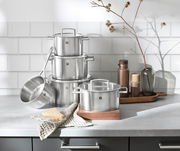 Topfset Vitality 5-tlg. aus Edelstahl, bestehend aus mehreren Töpfen und einer Stielkasserolle, auf einer Küchenarbeitsplatte arrangiert. Perspektive von vorne.