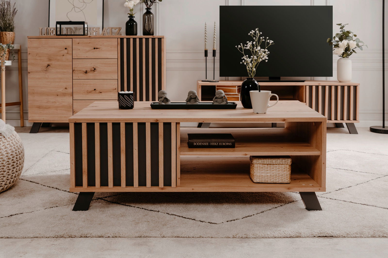 Moderner Couchtisch aus Holz mit schwarzen Akzenten, frontal fotografiert, dekoriert mit einer Vase, Tasse und Figuren.