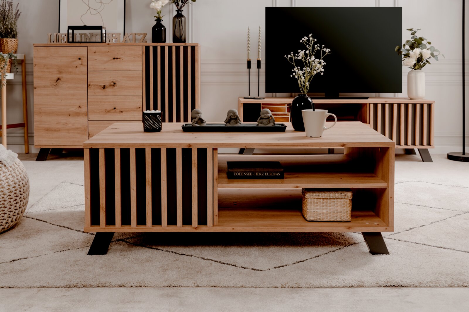 Moderne houten salontafel met zwarte accenten, gefotografeerd van voren, versierd met een vaas, een kopje en beeldjes.