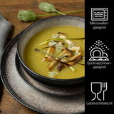 Nahaufnahme eines stilvoll angerichteten Suppentellers mit gelber Suppe und Pilzen, präsentiert auf einem mehrteiligen Tafelservice in Beige. Das Geschirr ist mikrowellengeeignet, spülmaschinengeeignet und lebensmittelecht.