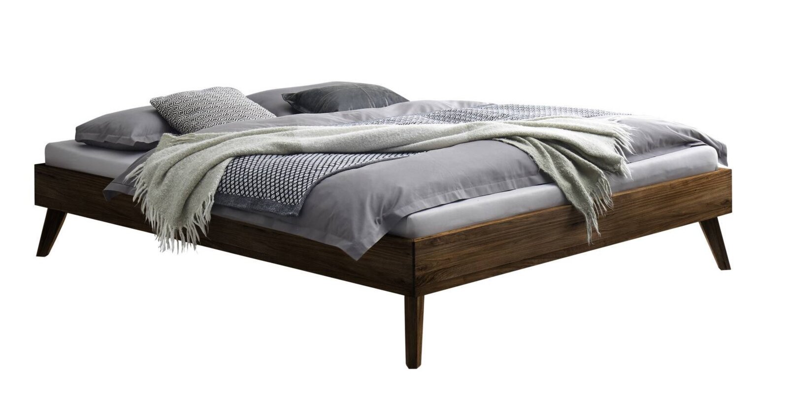 Modern laag houten bed in donkere houtlook met schuine poten, grijs beddengoed en deken, schuin vooraanzicht (3/4-perspectief)