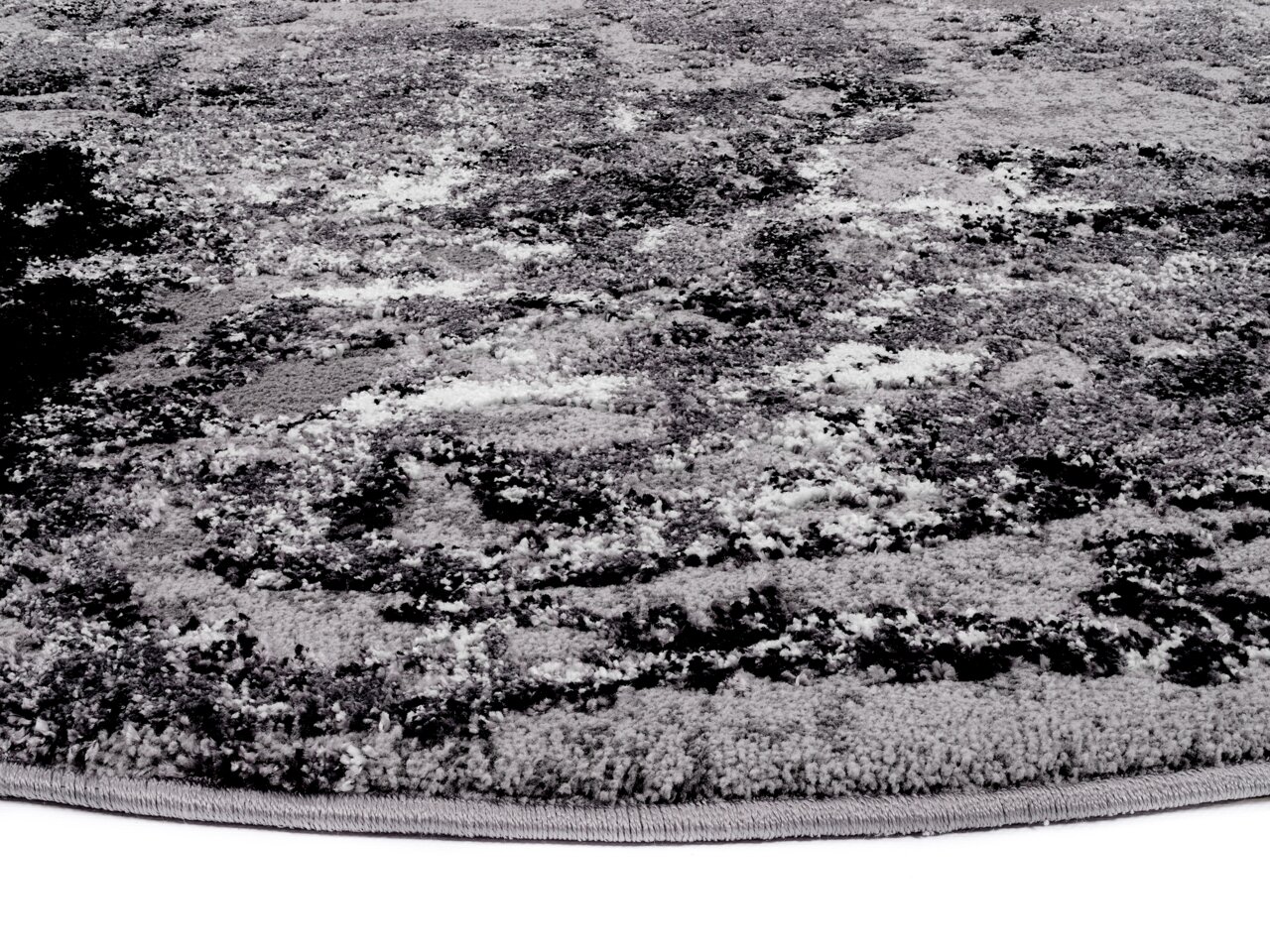 Nahaufnahme eines Designer Teppichs mit abstraktem Muster in Grautönen, seitliche Perspektive