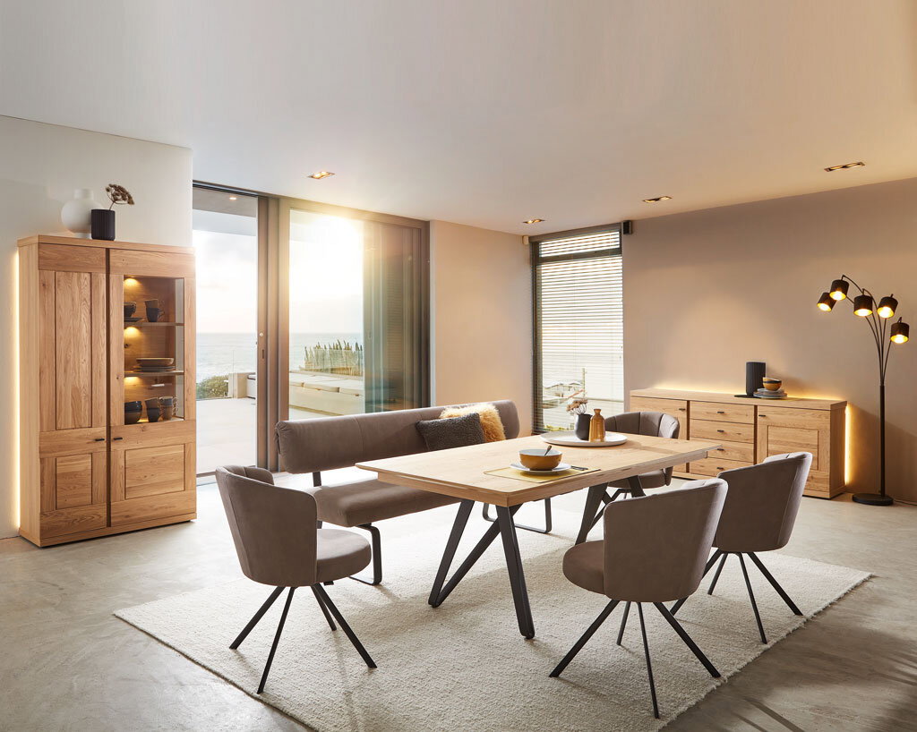 Moderner Essbereich mit Venjakob Esstisch, Vitrine und Sideboard in heller Holzoptik, seitliche Perspektive.