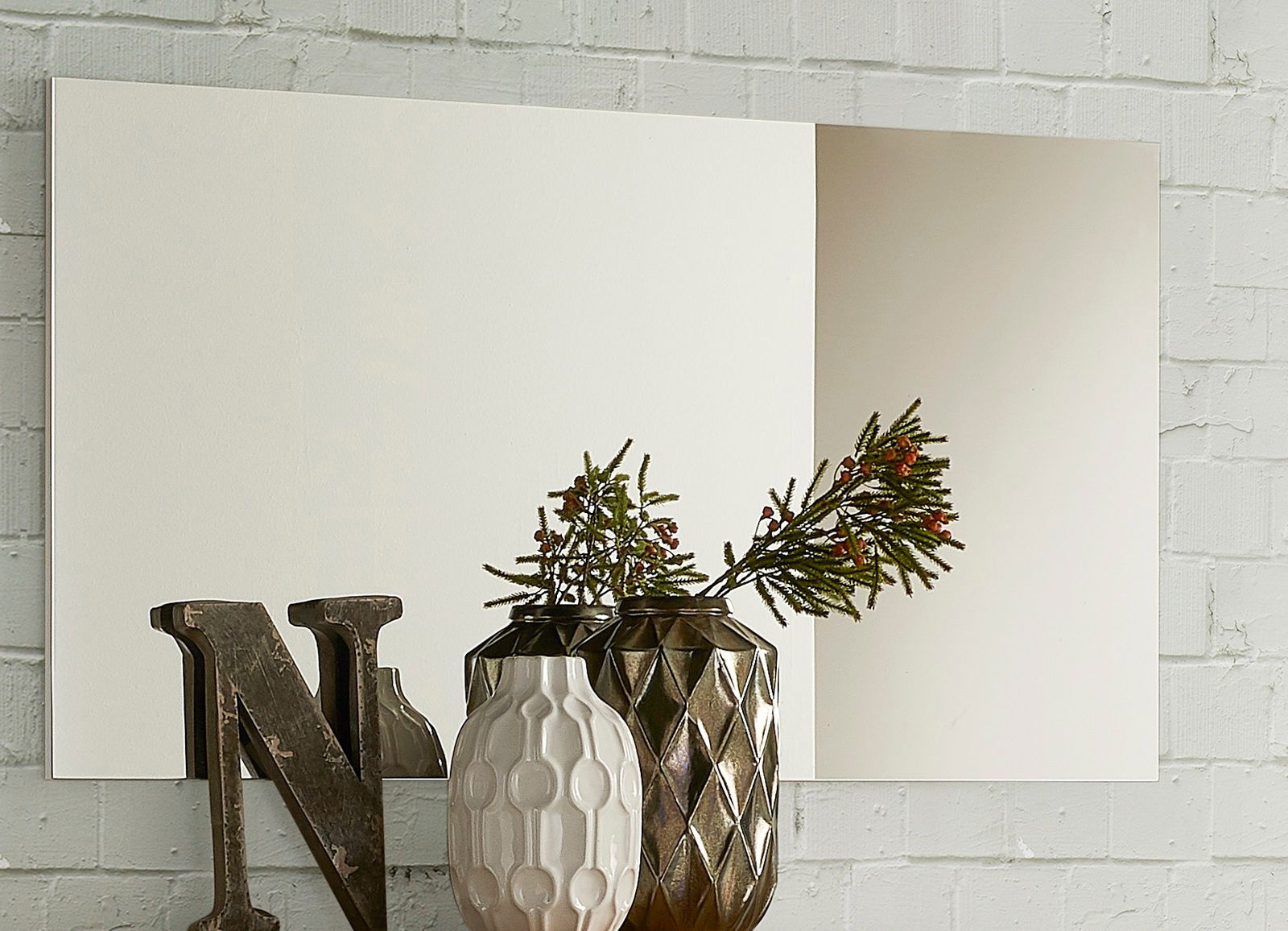 XL-Spiegel an einer Ziegelwand, dekoriert mit Vasen und einem Buchstaben, seitliche Perspektive