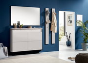 Moderner Eingangsbereich mit weißem Hängeschuhschrank und Garderobenpaneelen an einer blauen Wand, seitliche Perspektive.