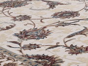 Nahaufnahme eines Orientteppichs mit floralen Mustern in Beige, Blau und Rot, seitliche Perspektive