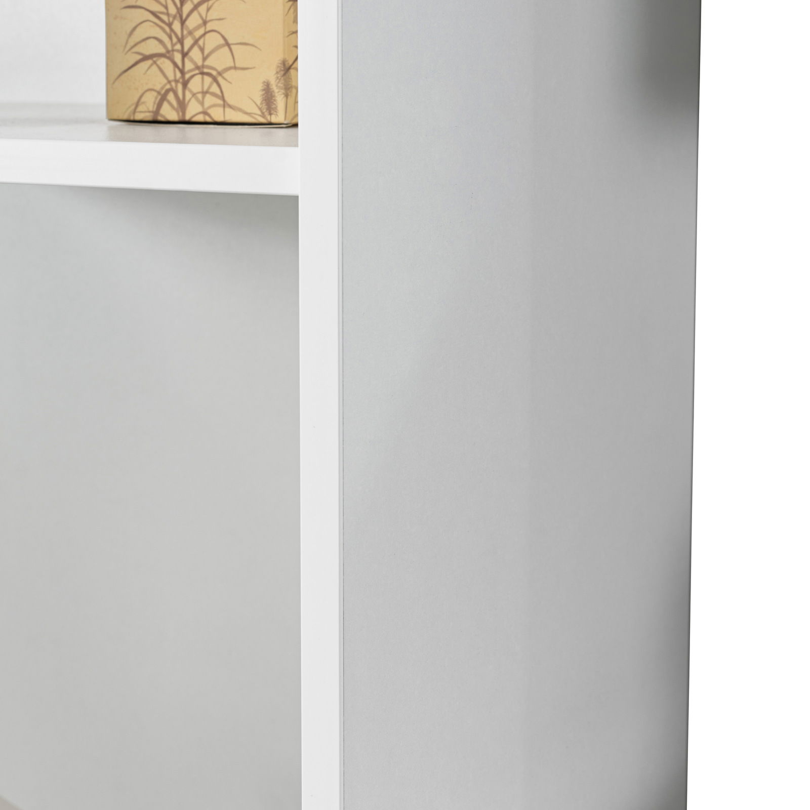 Nahaufnahme eines weißen Regals mit einem dekorativen Karton auf einem der Regalböden, seitliche Perspektive.