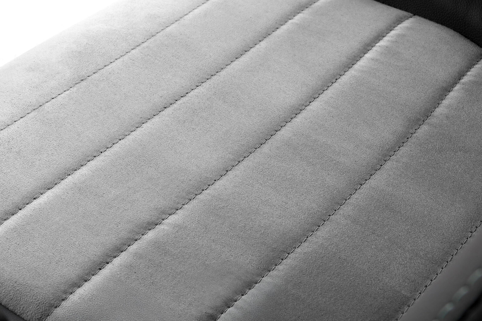 Nahaufnahme der gepolsterten Sitzfläche eines Gaming Stuhls in grauem Stoff, von oben betrachtet.