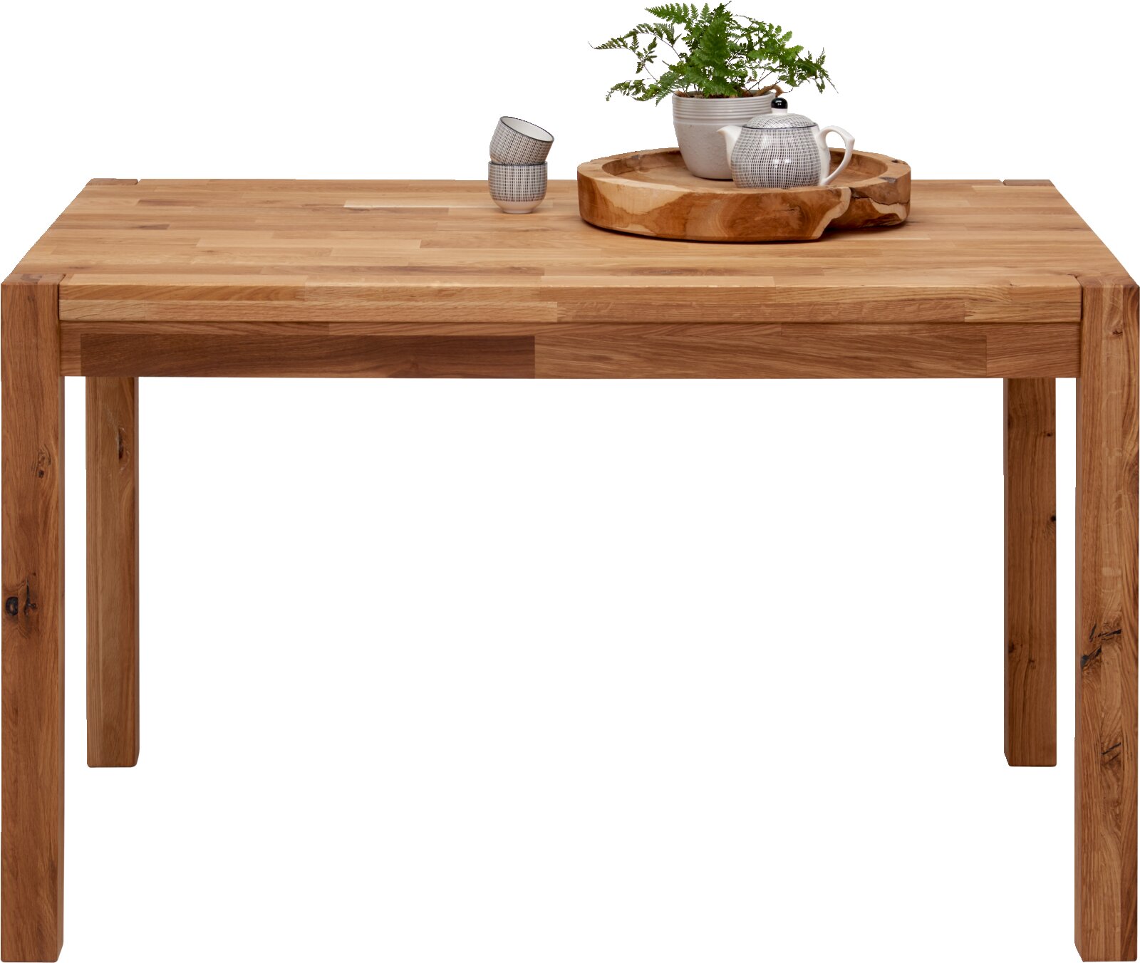 Linea Natura Eettafel TINA Esstisch aus Holz mit natürlicher Maserung, dekoriert mit einem Tablett, einer Teekanne und einer Pflanze, frontal betrachtet.
