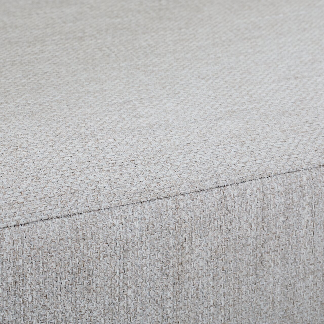 Nahaufnahme eines Loungesessels mit hellgrauem, strukturiertem Stoffbezug.