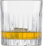 Nahaufnahme eines Whiskyglases mit geriffeltem Design, gefüllt mit goldenem Whisky und Eiswürfeln.