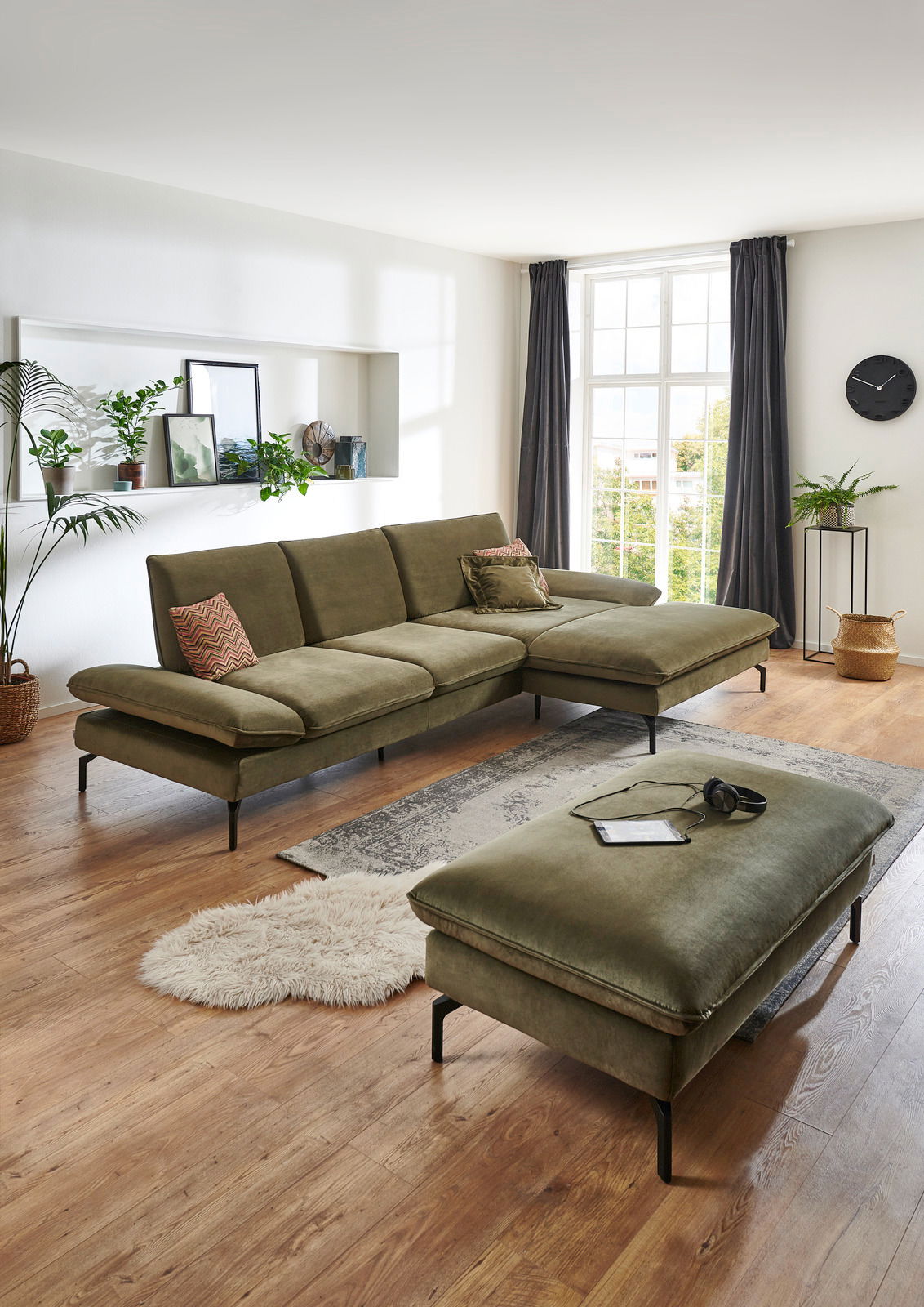 Moderano Hocker rechteckig ORLANDO Rechteckiger Hocker in einem modernen Wohnzimmer, aus olivgrünem Stoff mit schwarzen Metallbeinen, im Vordergrund der Perspektive.