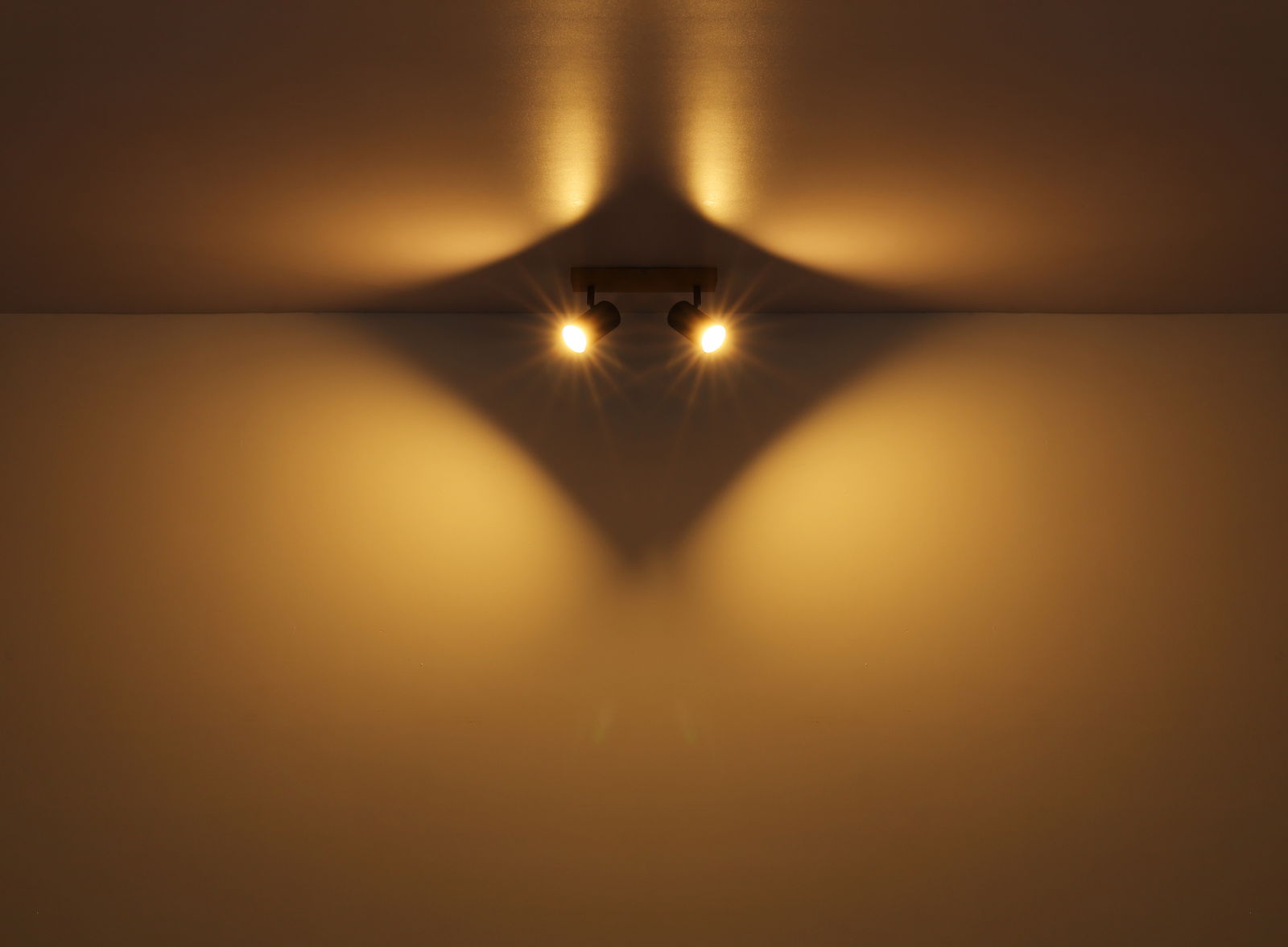 Zwei Strahler aus Metall in Graphit dunkel, an der Decke montiert, werfen warmes Licht und erzeugen ein interessantes Schattenspiel. Perspektive von unten.