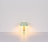 Moderne Tischleuchte mit grünem Schirm und Holzfuß, frontal beleuchtet.