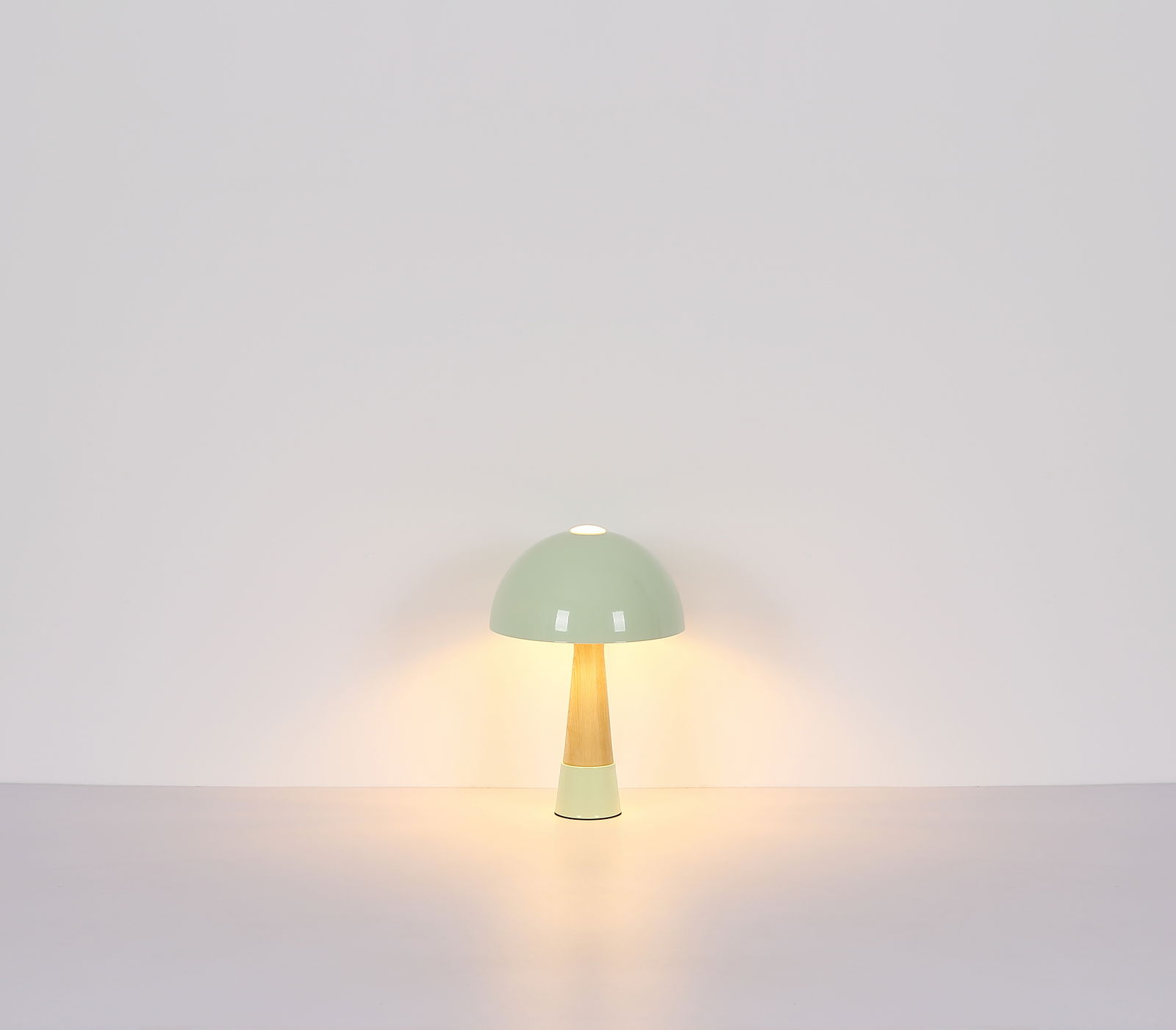 Moderne Tischleuchte mit grünem Schirm und Holzfuß, frontal beleuchtet.