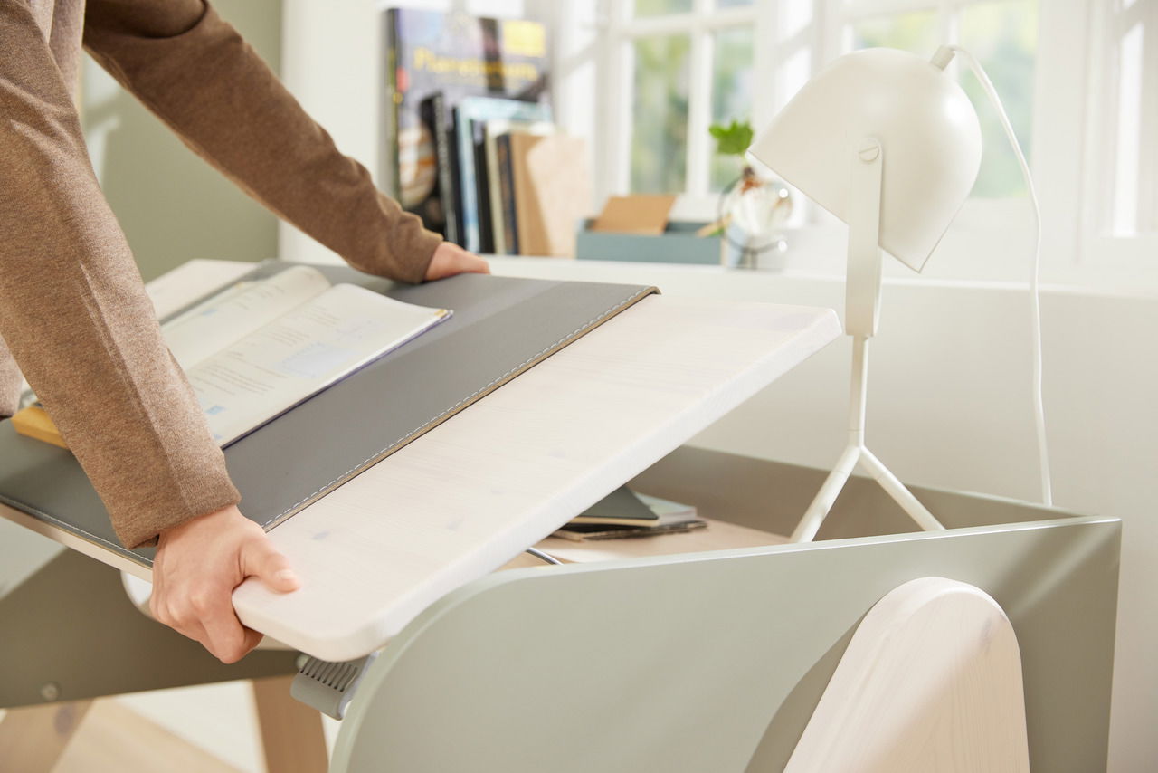 Schreibtisch-Auflage in einem modernen Büro, von der Seite betrachtet, mit einer Person, die sie anhebt.