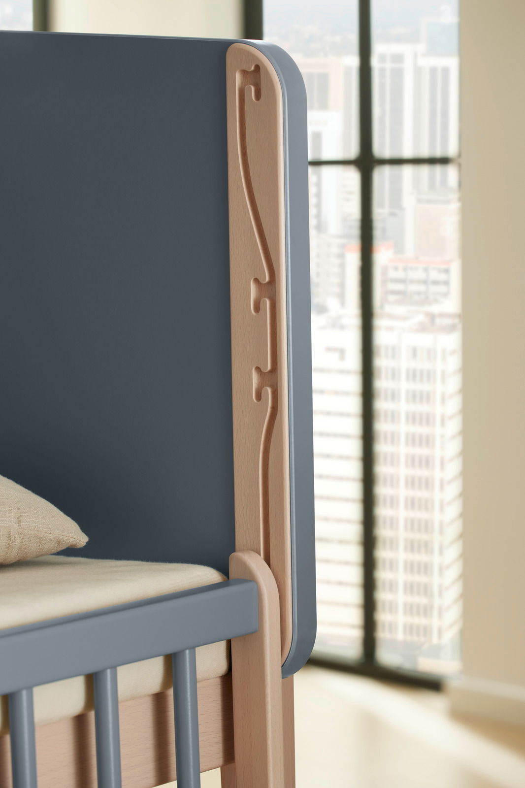 Detailansicht eines Anstellbetts mit grauem Rahmen und Holzverzierungen, seitliche Perspektive.