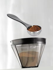 Kaffeemaß Misurino von oben, gefüllt mit gemahlenem Kaffee, neben einem Kaffeefilter.