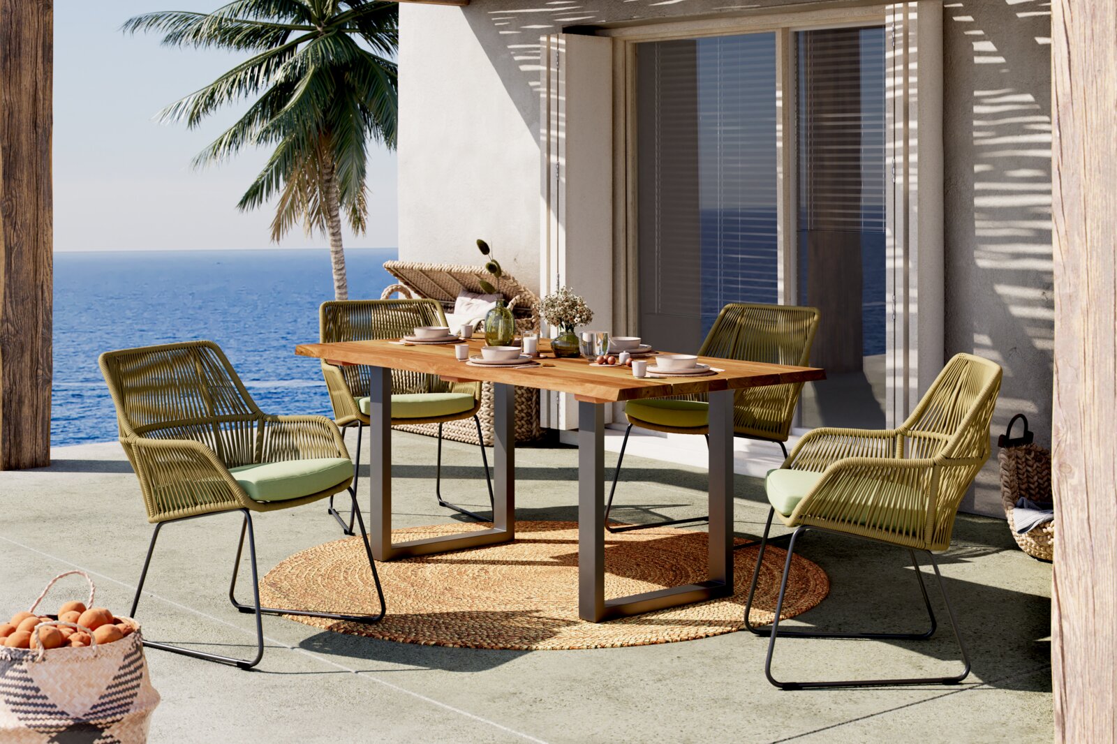 Amatio Gartensessel CHESTER 1 Outdoor-Essgruppe auf einer Terrasse am Meer: rechteckiger Holztisch mit Metallgestell und vier grüne Geflechtstühle mit Sitzkissen, seitliche Perspektive in leicht erhöhter Ansicht.