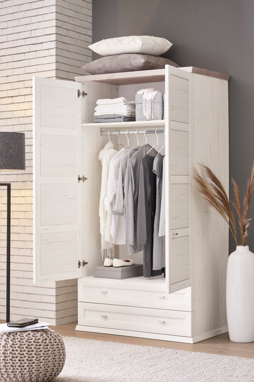 Offener XL-Garderobenschrank in heller Holzoptik, gefüllt mit Kleidung auf Kleiderbügeln und Accessoires, aus der Frontalperspektive fotografiert.