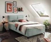 Modern boxbed in een stijlvol ingerichte slaapkamer met dakraam, gefotografeerd vanuit een zijaanzicht.