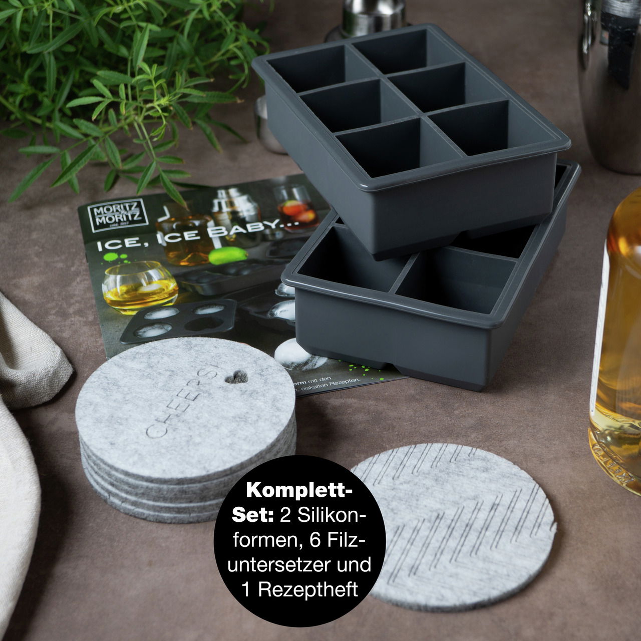Perspektive von oben auf ein Set mit zwei schwarzen Silikon-Eiswürfelformen, sechs grauen Filzuntersetzern und einem Rezeptheft.