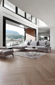 Moderne Longchairkombination in einem hellen Wohnzimmer mit Blick auf die Terrasse. Perspektive von vorne links.