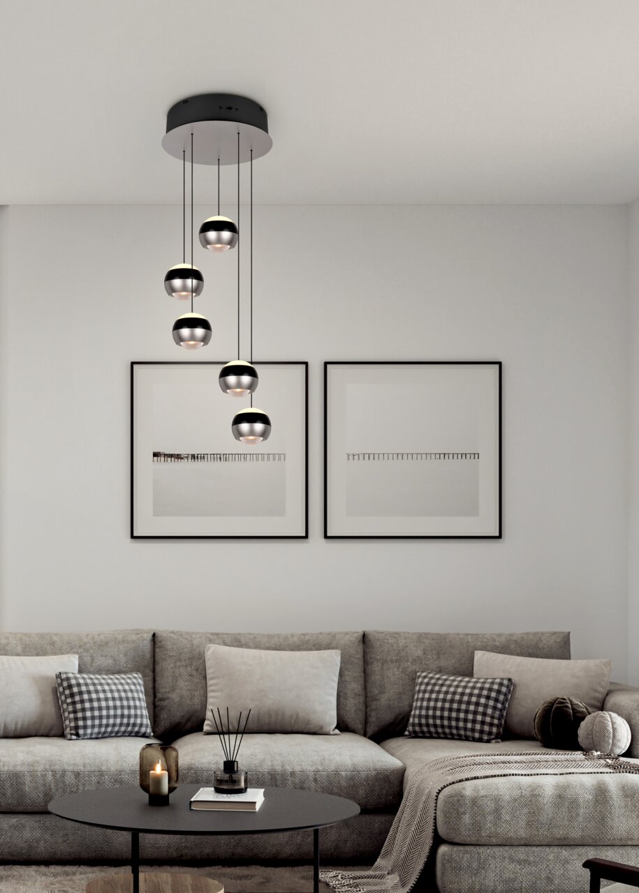 Moderne Pendelleuchte Orbit mit fünf kugelförmigen Lampen, hängend von einer schwarzen Deckenhalterung, in einem stilvollen Wohnzimmer mit grauem Sofa und minimalistischer Dekoration. Perspektive von vorne.