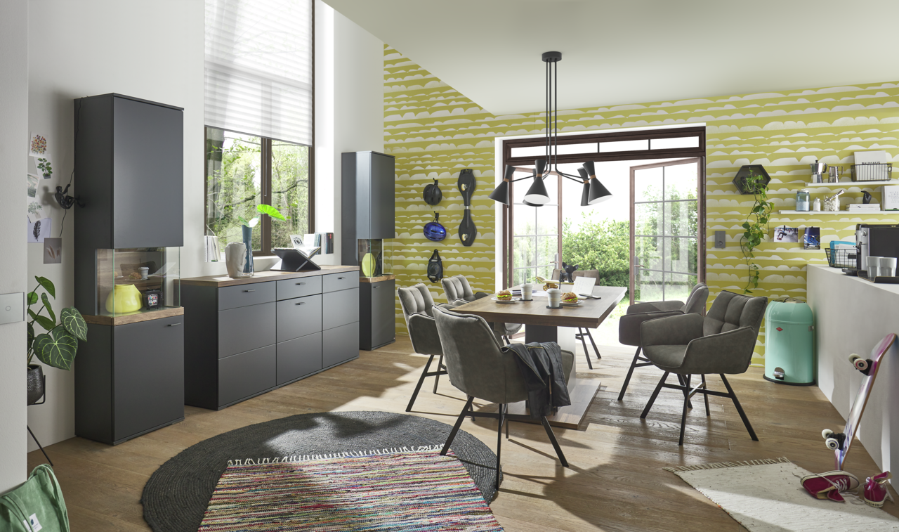 Moderner Essbereich mit Esstisch und Stühlen in einem hellen Raum mit großen Fenstern, seitliche Perspektive.