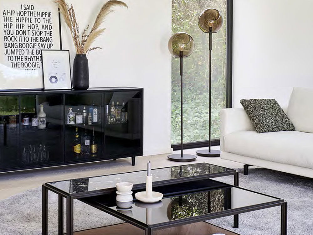 Das Titelbild der Complementsbroschüre zeigt ein Wohnzimmer mit einem schwarzen Schrank, Stehlampen und einem weißen Sofa.