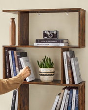 Modernes, dunkelbraunes Holz-Wandregal mit offenen Fächern, dekoriert mit Büchern, Vintage-Kamera, Vase und Topfpflanze; Frontansicht leicht von links.